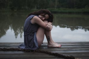 a woman sitting on a dock next to a body of water
